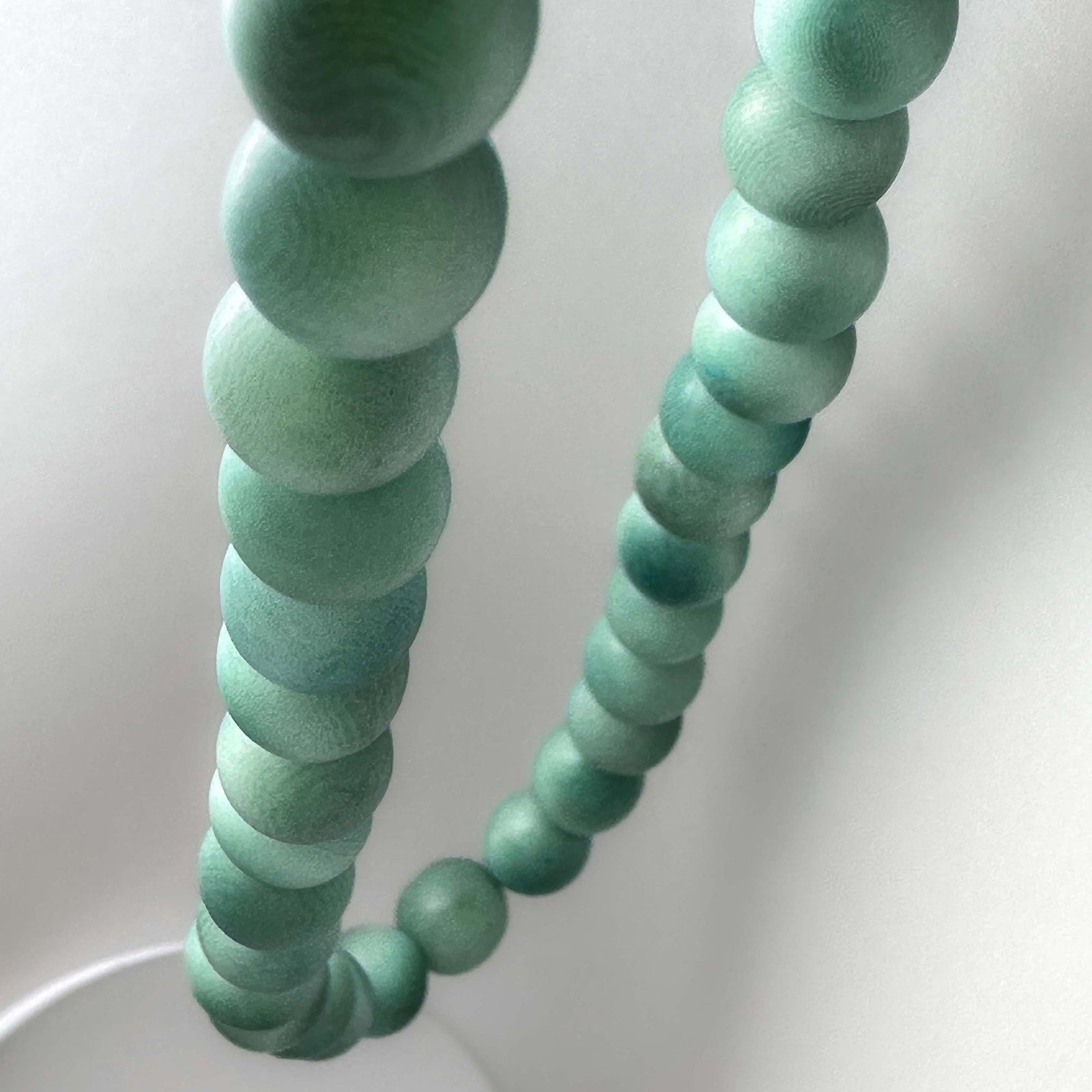 Close-up of a green beaded necklace on a white background